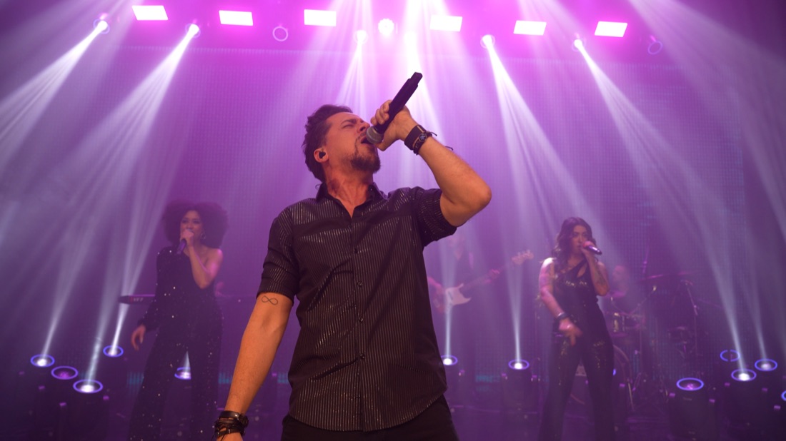 Vocalista e banda da Banda Prime em show com iluminação roxa
