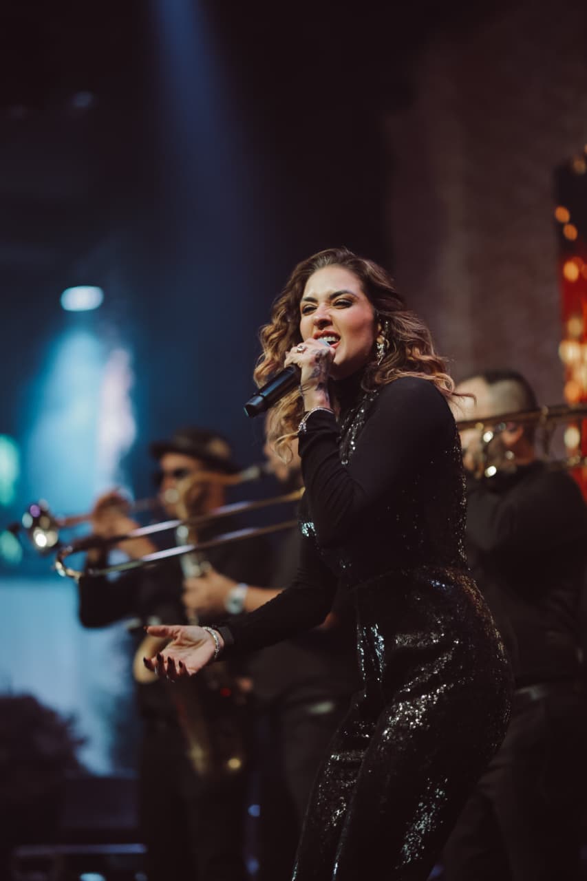 Vocalista da Banda Prime cantando com naipe de metais ao fundo